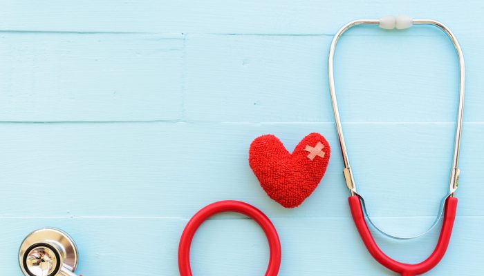 World health day, Healthcare and medical concept. Woman hand holding red heart with Stethoscope, notepad or notebook, thermometer and yellow Pill on Pastel white and blue wooden table background texture.